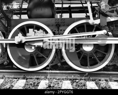 Zwei Räder nachrüsten. Schwellen und Schienen, Mechanismen, Kolben und Führungen. Lokomotive des 19. Frühen 20. Jahrhunderts mit Dampfmaschine. Vintage-Style. Schwarzweißfoto. Schöne Karte. Stockfoto