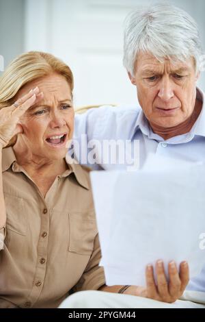 Wie ist das möglich? Ein älteres Ehepaar, das frustriert aussah, als es seinen Papierkram zusammen durchging. Stockfoto