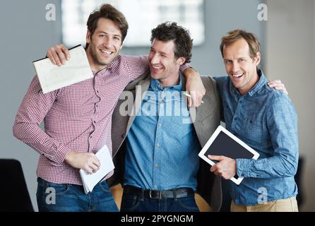 Die Jungs sind wieder im Geschäft. Porträt einer Gruppe lachender Kollegen, die Arm in Arm in einem Büro stehen. Stockfoto