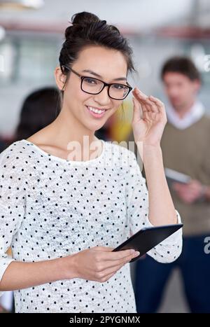 Der intelligente Schachzug für Kreativprofis. Intelligente junge Frau, die in der Hand eines digitalen Tablets vor der Kamera lächelt. Stockfoto