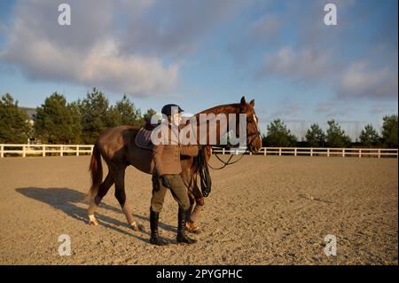 Weibliche Reiterin, die nebeneinander reitet und einen Sattelgurt hält Stockfoto