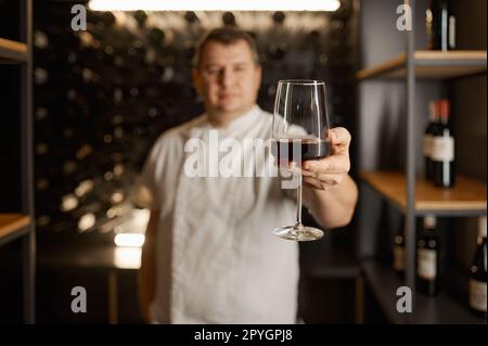 Erfolgreicher männlicher Sommelier, der den Geschmack verkostet und die Weinqualität prüft Stockfoto