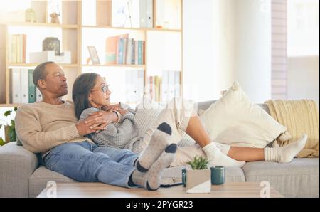 Seniorenpaar, entspannen und Sofa zum Umarmen, Denken oder Gedächtnis an das Leben, Liebesgedächtnis oder zum Binden im Wohnzimmer. Reifer Mann, alte Frau und umarmen Sie sich auf der Lounge-Couch für Vision, Pflege oder Unterstützung in Florida Stockfoto