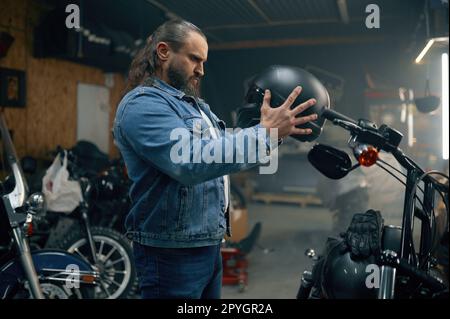 Seitenansicht des Motorradfahrers bei der Auswahl eines neuen, modernen Schutzhelms im Motorradladen Stockfoto
