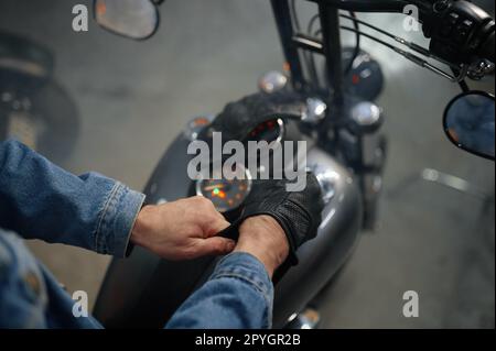 Nahaufnahme der Biker-Hand mit Lederhandschuhen über dem Motorradtank Stockfoto