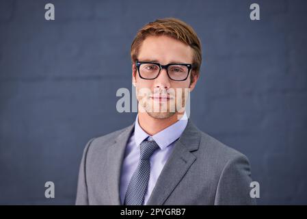 Er ist stilvoll und erfolgreich. Porträt eines gutaussehenden jungen Geschäftsmanns, der vor grauem Hintergrund steht. Stockfoto