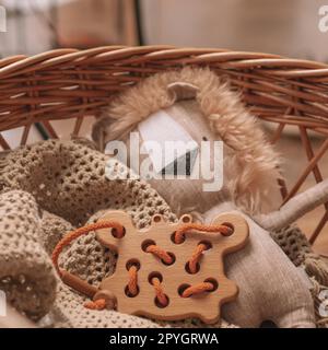 Spielzeug aus Holz für Kinder mit Löchern zum Lernen Schnürung mit orangefarbener Kordel auf beiger Decke in einem Korb mit Löwenspielzeug Stockfoto