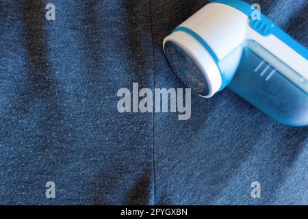 Moderner Rasierer auf grauem Tuch. Dieses Gerät entfernt Fusseln von der Kleidung. Stockfoto