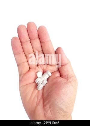 Eine Handvoll weißer Pillen in der Hand auf weißem Hintergrund Stockfoto