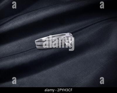 Nahaufnahme des eleganten Diamantrings auf schwarzem Stoffhintergrund Stockfoto