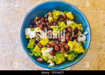 Hausgemachte Bohnen-Avocado und Zwiebelsalat in blauer Schüssel Mexiko. Stockfoto