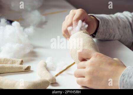 Nahaufnahme gekürzte Frau, Schneiderhände nähen und weiche Spielzeuge in der Werkstatt nähen. Kleine Unternehmen, kreative Beschäftigung. Stockfoto