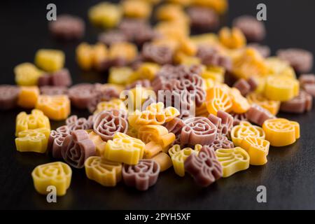 Pasta in verschiedenen unheimlichen Formen. Ungekochte halloween-Pasta auf schwarzem Tisch. Stockfoto