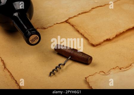 Flasche Wein mit Kork und Öffner auf braunem Papier Stockfoto