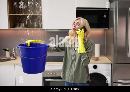 Frau Ruft Klempner An, Während Sie Wasser Sammelt Stockfoto