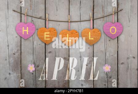 Hallo April auf hängende pink und orange Herzen geschrieben und verwitterte Holz- Hintergrund, mit Blumen Stockfoto