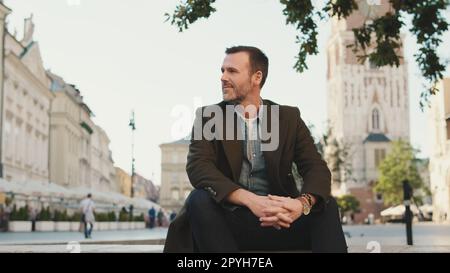 Ein bärtiger Mann, der auf dem Platz der Altstadt sitzt Stockfoto