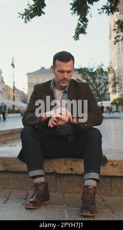 Ein bärtiger Mann, der auf dem Platz der Altstadt sitzt Stockfoto