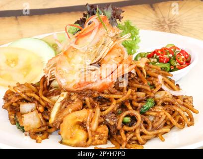 Gebratene Nudeln, Mah Goreng oder mi Goreng, serviert mit Garnelen. Beliebtes Gericht in Südostasien. Stockfoto