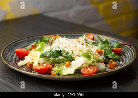 Caesar-Salat in dunklem Ton auf einem Holztisch Stockfoto