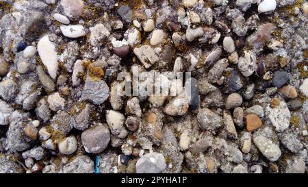 Natursteinhintergrund mit strukturierter Oberfläche und grünem Moos. Mustermineralien mit grober Struktur und gelben Flechten. Alternde, farbenfrohe Bergkulisse. Natursteinoberfläche mit leerem Platz für Text Stockfoto