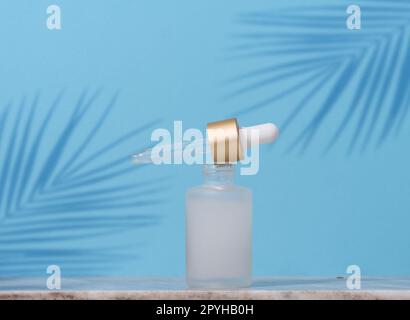 Tropfflasche aus weißem Glas mit kosmetischem Mittel auf blauem Hintergrund Stockfoto