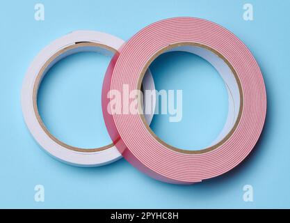 Zwei Rollen doppelseitiges Klebeband auf blauem Hintergrund, Draufsicht Stockfoto