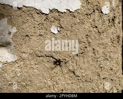 Nahhintergrund der Wand eines alten Hauses aus Ton und Stroh. Alte Bauart. Tonwand aus Stroh und Schlamm. Gülle mit Ton vermischt und als Baumaterial getrocknet Stockfoto