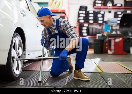 Der qualifizierte Mechaniker wechselt die Reifen des Fahrzeugs im Autodienst Stockfoto