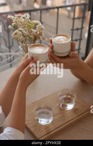 Freunde trinken Kaffee an einem Holztisch im Café, schließen Stockfoto