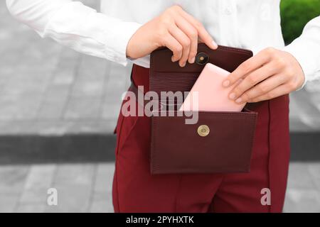 Eine Frau, die im Freien einen Kosmetikspiegel aus der Tasche nimmt, Nahaufnahme. Platz für Text Stockfoto