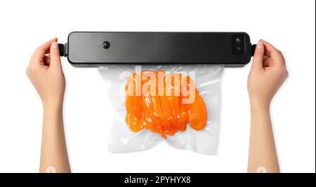 Frau, die Versiegelung für Vakuumverpackungen verwendet, mit Plastikbeutel mit Paprika auf weißem Hintergrund, Draufsicht Stockfoto