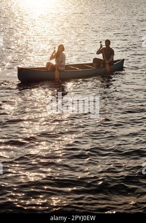 Fahren Sie zum See und genießen Sie Abenteuer. Ein junges Paar, das ein Boot auf dem See rudert. Stockfoto