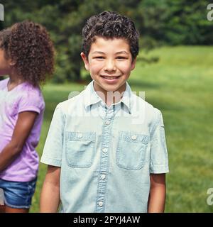 Sie werden uns nicht vor dem fernseher sitzen sehen. Ein kleiner Junge, der mit seinen Freunden im Park rumhängt. Stockfoto