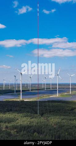 PRODUKTION - 03. Mai 2023, Brandenburg, Klettwitz: Der 300 Meter hohe Windmast erhebt sich in den Himmel auf dem Hochplateau in Klettwitz bei Schipkau (Oberspreewald-Lausitz) (Luftaufnahme mit einer Drohne). Im Hintergrund sind viele Windturbinen sowie mehrere Photovoltaik-Anlagen zu sehen. Am 04.05.2023 findet die Inbetriebnahme des weltweit höchsten Windmessmastes statt. Bei einer Höhe von 300 Metern wird die Windversorgung in den nächsten 12 Monaten systematisch ermittelt. Die Ergebnisse dieses Projekts werden die Grundlage für künftige Hochwasser-Windkrafttürme bilden. Das Hier Stockfoto
