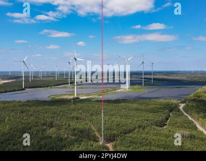 PRODUKTION - 03. Mai 2023, Brandenburg, Klettwitz: Der 300 Meter hohe Windmast erhebt sich in den Himmel auf dem Hochplateau in Klettwitz bei Schipkau (Oberspreewald-Lausitz) (Luftaufnahme mit einer Drohne). Im Hintergrund sind viele Windturbinen sowie mehrere Photovoltaik-Anlagen zu sehen. Am 04.05.2023 findet die Inbetriebnahme des weltweit höchsten Windmessmastes statt. Bei einer Höhe von 300 Metern wird die Windversorgung in den nächsten 12 Monaten systematisch ermittelt. Die Ergebnisse dieses Projekts werden die Grundlage für künftige Hochwasser-Windkrafttürme bilden. Das Hier Stockfoto