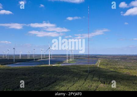 PRODUKTION - 03. Mai 2023, Brandenburg, Klettwitz: Der 300 Meter hohe Windmast erhebt sich in den Himmel auf dem Hochplateau in Klettwitz bei Schipkau (Oberspreewald-Lausitz) (Luftaufnahme mit einer Drohne). Im Hintergrund sind viele Windturbinen sowie mehrere Photovoltaik-Anlagen zu sehen. Am 04.05.2023 findet die Inbetriebnahme des weltweit höchsten Windmessmastes statt. Bei einer Höhe von 300 Metern wird die Windversorgung in den nächsten 12 Monaten systematisch ermittelt. Die Ergebnisse dieses Projekts werden die Grundlage für künftige Hochwasser-Windkrafttürme bilden. Das Hier Stockfoto
