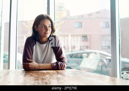 Sie kommt gerne her, nur um nachzudenken. Eine attraktive junge Frau, die tief in Gedanken in einem Café sitzt. Stockfoto