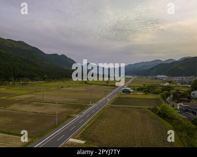 Offene Straße durch ein ländliches japanisches Dorf im Bergtal bei Sonnenuntergang Stockfoto
