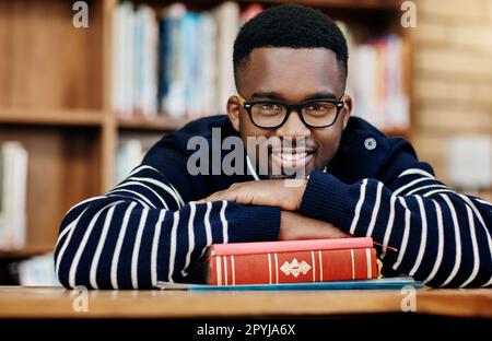 Ich muss los. Porträt eines fröhlichen Universitätsschülers, der in der Bibliothek auf dem Campus sitzt. Stockfoto