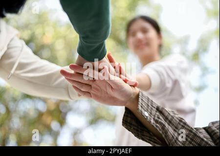 Nahaufnahme verschiedener junger Menschen, die ihre Hände zusammenlegen, um sich aufzuheitern. Jugend, Freundschaft, Feiern Stockfoto