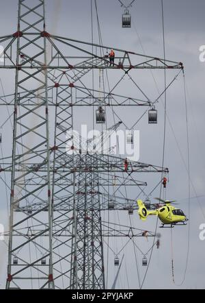 PRODUKTION - 03. Mai 2023, Schleswig-Holstein, Klixbüll: Ein Hubschrauber fliegt zwischen den Strommasten des letzten Bauabschnitts der Westküsten-Pipeline, während die so genannten Führungskabel eingezogen werden. Der Hubschrauber wird verwendet, um leichte Kunststoffkabel von einem Pol zum anderen zu fliegen, während industrielle Monteure das Führungskabel durch die Rollen an den Enden der Pole führen. Die Westküstenstrecke - eine 380-Kilovolt-Überlandleitung - wird über eine Gesamtlänge von etwa 140 km zwischen Brunsbüttel und der dänischen Grenze und von dort aus weiter verlaufen. Foto: Christian Charisius/dpa Stockfoto