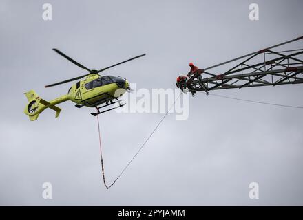 PRODUKTION - 03. Mai 2023, Schleswig-Holstein, Klixbüll: Ein Hubschrauber fliegt zwischen den Strommasten des letzten Bauabschnitts der Westküsten-Pipeline, während die so genannten Führungskabel eingezogen werden. Der Hubschrauber wird verwendet, um leichte Kunststoffkabel von einem Pol zum anderen zu fliegen, während industrielle Monteure das Führungskabel durch die Rollen an den Enden der Pole führen. Die Westküstenstrecke - eine 380-Kilovolt-Überlandleitung - wird über eine Gesamtlänge von etwa 140 km zwischen Brunsbüttel und der dänischen Grenze und von dort aus weiter verlaufen. Foto: Christian Charisius/dpa Stockfoto