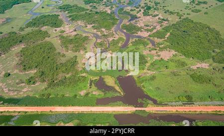 Luftaufnahme der Transpantaneira-Feldstraße, die eine Lagune über eine kleine Brücke in der typischen Landschaft der North Pantanal Feuchtgebiete, Mato Grosso, Brazi, überquert Stockfoto