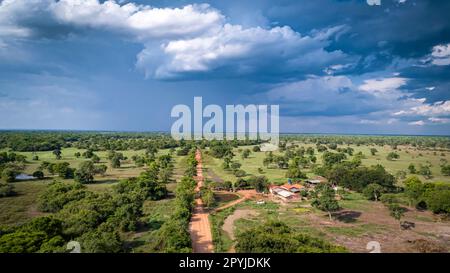 Luftaufnahme der Transpantaneira Schotterstraße mit dramatischem Himmel und Regen, die die typische Landschaft in den North Pantanal Wetlands, Mato Grosso, Brasilien, durchquert Stockfoto