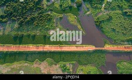 Luftaufnahme der Transpantaneira-Feldstraße, die einen Fluss durch eine Holzbrücke überquert, üppige Vegetation rund um North Pantanal Wetlands, Mato Grosso, Brasilien Stockfoto
