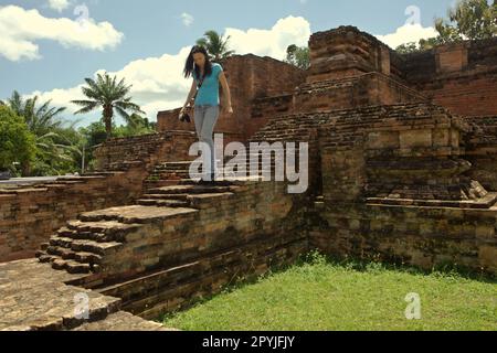 Ein Reiseleiter wird am Wat Long Tempel in Chaiya, Surat Thani, Thailand fotografiert. Basierend auf der so genannten Wat Sema Mueang Inschrift (775 n. Chr.) werden Wat Long – zusammen mit Wat Kaeo und Wat Wiang in der Nähe – als die „drei Tempel“ bezeichnet, die unter dem Kommando von Maharaja von Srivijaya aus der Sailendra-Dynastie errichtet wurden. Diese Tempel wurden in der Ayutthaya-Zeit (14.-18. Jahrhundert) kontinuierlich dekoriert und verwendet. Stockfoto