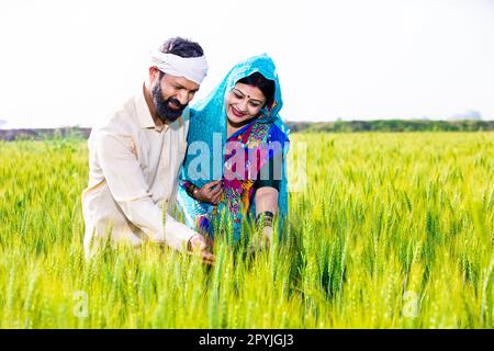 Glückliches, junges indisches Bauernpaar, das Weizen anfasst, steht auf dem Feld an einem sonnigen Tag. Speicherplatz kopieren. Das Konzept des ländlichen indiens. Stockfoto