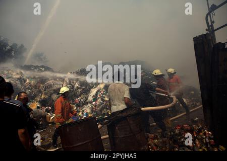 Mitglieder der Feuerwehrmannschaft von Jakarta und lokale Personen, die die Abkühlphase durchführten, nachdem ein Feuerunfall Lagergebäude einer Heimindustrie in Kebayoran Lama, Süd-Jakarta, Jakarta, Indonesien, niedergebrannt hatte. Stockfoto