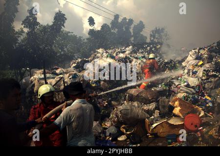 Mitglieder der Feuerwehrmannschaft von Jakarta und lokale Personen, die die Abkühlphase durchführten, nachdem ein Feuerunfall Lagergebäude einer Heimindustrie in Kebayoran Lama, Süd-Jakarta, Jakarta, Indonesien, niedergebrannt hatte. Stockfoto